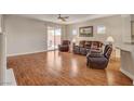 Open living room with wood floors, cozy seating, and sliding glass doors to the patio at 7152 Fairwind Acres Pl, Las Vegas, NV 89131