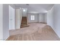 Spacious carpeted living room features stairs, neutral tones, and natural light at 7892 Villa Salsa Ave, Las Vegas, NV 89131