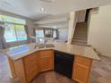 Kitchen area with stone countertops, a dual sink, black appliances, and access to the staircase and other rooms at 1564 Silver Knoll Ave, Las Vegas, NV 89123