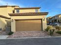 Two-car garage featuring a brick driveway and exterior lighting at 2456 Bagnara Pl, Henderson, NV 89044