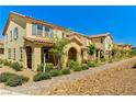 Street view of new townhomes with arched entryways, tile roofs and desert landscaping at 2456 Bagnara Pl, Henderson, NV 89044