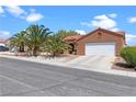 Single-story home featuring a terracotta roof, palm trees, an attached two-car garage, and well-maintained landscaping at 608 Blooming View Ave, North Las Vegas, NV 89032
