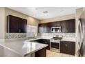 Well-lit kitchen featuring dark cabinetry, stainless steel appliances, and stylish tile backsplash at 971 Whispering Grove Ave, Las Vegas, NV 89123