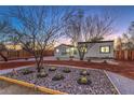 Charming single-story home at dusk with desert landscaping and a manicured yard with a wooden fence at 1731 Sherwin Ln, Las Vegas, NV 89156