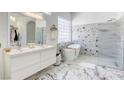 Bright bathroom featuring double sinks, a soaking tub, a walk-in shower, and marble flooring at 3064 Azure Bay St, Las Vegas, NV 89117