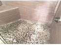 Custom shower featuring a river rock floor and neutral-tone wall tiles at 8455 W Sahara Ave # 213, Las Vegas, NV 89117