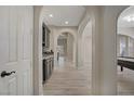 Elegant hallway featuring arched doorways, light wood-look tile flooring, and a built-in bar area at 8544 Garden Valley Ct, Las Vegas, NV 89178