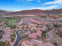 An elevated view of a residential community nestled next to a golf course and a scenic mountain range at 1 Cerchio Basso, Henderson, NV 89011