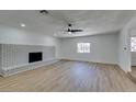 A spacious living room featuring light wood floors, a white brick fireplace, and a ceiling fan at 212 View Dr, Las Vegas, NV 89107