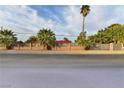 View of a fenced property with mature trees and palm trees, offering a sense of privacy and seclusion at 2926 E Eldorado Ln, Las Vegas, NV 89120