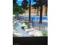 Resort-style pool area with a beautiful rock waterfall and lush landscaping creating a tranquil oasis at 3394 Brookfield Dr, Las Vegas, NV 89120