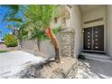 Close up of the double door home entrance with stone pillars and a well manicured palm tree at 3728 Richard Allen Ct, Las Vegas, NV 89147