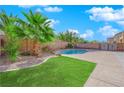A landscaped backyard featuring a well manicured lawn, trees, a pool and a cemented patio at 4063 Lower Saxon Ave, North Las Vegas, NV 89085