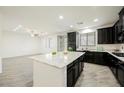 Open-concept kitchen featuring a center island, black cabinets, and stainless steel appliances at 12426 Mosticone Way, Las Vegas, NV 89141