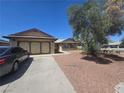 Exterior of the home featuring a spacious driveway, attached garage, and desert landscaping at 2921 Mitzi Ave, Las Vegas, NV 89101