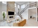 Bright living room featuring a stone fireplace, high ceilings, and a staircase with decorative iron railings at 350 Gandara St, Las Vegas, NV 89138