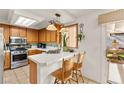 Bright kitchen featuring wood cabinets, stainless steel appliances, tile counters, and a view to the backyard fountain at 9522 Arrowhead Falls Ct, Las Vegas, NV 89148