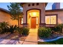 Covered front entry with an arched entryway, desert landscaping, and a decorative front door at 2547 Serenity Hollow Dr, Henderson, NV 89052
