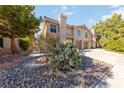 View of the stucco home, desert landscaping, and driveway leading to the two-car garage at 2834 Crystal Lantern Dr, Henderson, NV 89074