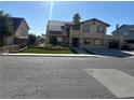 Two-story home featuring solar panels, a two-car garage, green front yard, and a tan exterior at 4356 Sabadell St, Las Vegas, NV 89121
