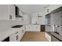 Bright kitchen featuring modern appliances, white cabinets, a stylish black range hood, and hardwood flooring at 9512 Quail Ridge Dr, Las Vegas, NV 89134