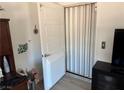 View of a white door opening to reveal an accordion style door with a floral arrangement nearby at 965 Nevada State Dr # 15104, Henderson, NV 89002