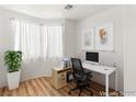 Staged office space with a desk, chair, and a plant near a large window allowing natural light at 9688 Meeks Bay Ave, Las Vegas, NV 89148