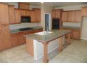 Spacious kitchen with wood cabinets, tile floors, granite countertops, and an island with sink at 981 Buffalo River Ave, Henderson, NV 89002
