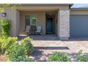 Close-up of a cozy front porch with seating, a decorative stone accent wall, and a stylish front door at 10049 Cardinal Knoll Ave, Las Vegas, NV 89143