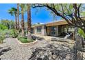 Serene backyard with stone landscaping, palm trees, and covered patio at 10237 Andante Ct, Las Vegas, NV 89135