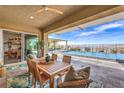 A covered back patio with a wood table sits next to the pool and offers scenic views at 11238 Rebel Dome Ct, Las Vegas, NV 89141