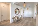 A welcoming foyer with wood floors is decorated with a round mirror, bench, and pendant lights at 11238 Rebel Dome Ct, Las Vegas, NV 89141