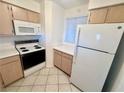 Compact kitchen featuring light wood cabinets, white appliances and tile flooring at 2064 Mesquite Ln # 102, Laughlin, NV 89029