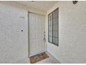 Close-up of the front door and entrance to unit 204 with a small window and 'Welcome' mat at 2633 S Durango Dr # 204, Las Vegas, NV 89117
