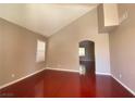 Bright living room featuring vaulted ceilings, fresh paint, wood-look flooring, and arched doorway at 2694 Rimpacific Cir, Las Vegas, NV 89146