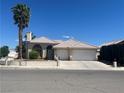 Beautiful stucco home with a tile roof, two-car garage, and manicured landscaping on a sunny day at 3136 Jane Austin Ave, North Las Vegas, NV 89031