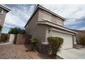 Two-story home featuring desert landscaping, a two-car garage, and a tile roof under a cloudy blue sky at 3440 Crystal Tower St, Las Vegas, NV 89129