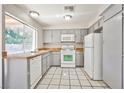 A well-lit kitchen with gray cabinets, white appliances, a window, and tile floors at 3596 Bronco Rd, Las Vegas, NV 89103