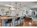 Modern kitchen with a breakfast bar featuring pendant lighting and wood laminate floors, seamlessly connecting to the living area at 7960 Quarter Horse Ave, Pahrump, NV 89061
