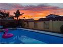 Relaxing backyard pool view at sunset with a pink flamingo float and poolside lounge area near a stucco fence at 1440 Rawhide Rd, Boulder City, NV 89005
