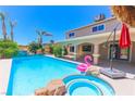 Stunning backyard pool with a built-in jacuzzi, waterfall features, swaying palm trees, and an inflatable flamingo at 1440 Rawhide Rd, Boulder City, NV 89005