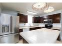 Bright kitchen featuring stainless steel appliances, dark cabinets, tile countertops, and decorative pendant lighting at 2825 Burnham Ave, Las Vegas, NV 89169