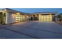 Expansive driveway leads to two two-car garages with modern doors, stone accents and desert landscaping at 4070 N Tee Pee Ln, Las Vegas, NV 89129