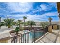 Balcony view of a backyard featuring a sparkling pool and spa, surrounded by mature palm trees at 5949 Casa Coronado Ave, Las Vegas, NV 89131