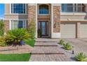 Inviting front entrance featuring brick walkway, stone accents, and lush landscaping at 7112 Rancho De Taos Ct, Las Vegas, NV 89130