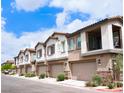 View of townhome exteriors with garages and desert landscaping on a sunny day at 7342 N Decatur Blvd # 5, Las Vegas, NV 89131