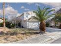 Two-story home with a three-car garage, tile roof, and desert landscaping under a partly cloudy sky at 1924 Coralino Dr, Henderson, NV 89074
