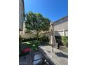 Landscaped backyard featuring well-manicured grass, an outdoor patio set, shaded by a tree, and surrounded by a white fence at 9082 Amanda Creek Ct, Las Vegas, NV 89149