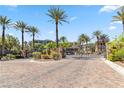 Community entrance with paved street, palm trees, ornamental plants, and an ornate wrought iron gate at 9125 Las Manaitas Ave # 302, Las Vegas, NV 89144