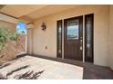 Front door featuring glass windows and a tile front porch, columns, and a wall with green plants at 10948 Carberry Hill St, Las Vegas, NV 89141